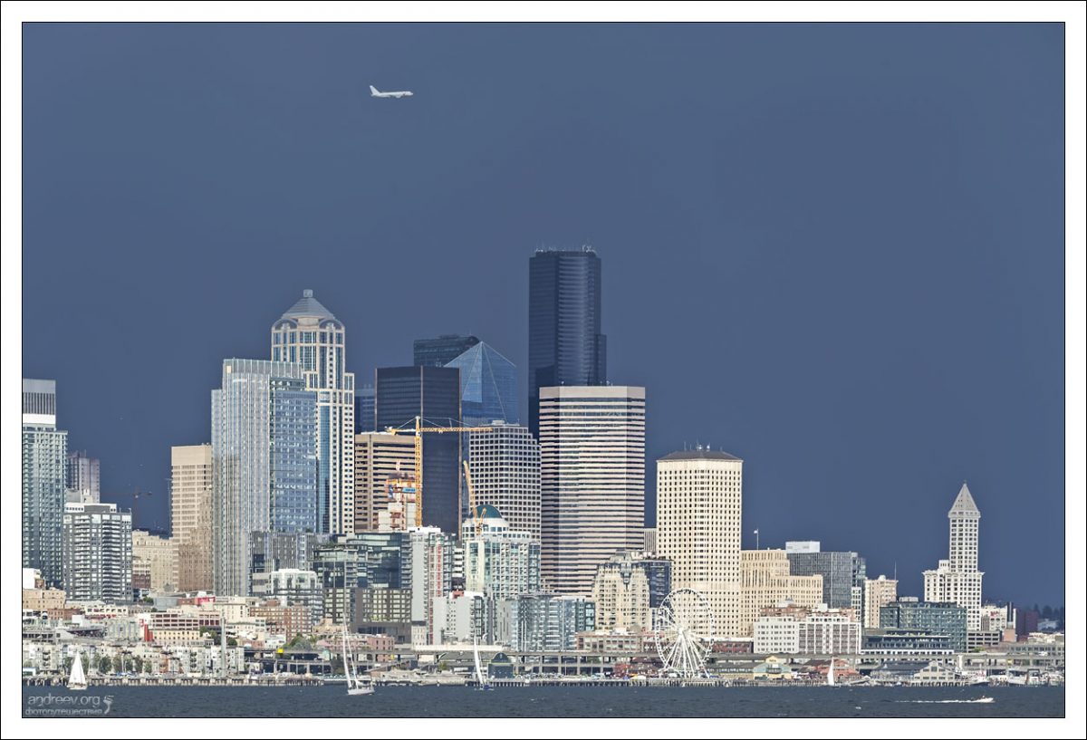 Центр Сиэтла и летящий над ним самолет.