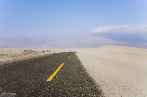 Песок с белоснежных дюн частично заползает на дорогу.