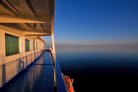 Закатные солнечные лучи отражаются от начищенной палубы теплохода.