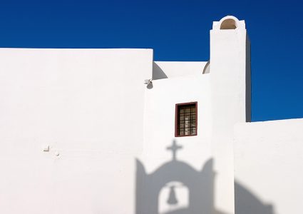 Тень от колокола на белоснежной стене одного из домов в Ие.