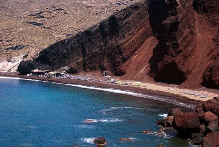 Красный пляж под гигантским утесом. Одежда - опционально .