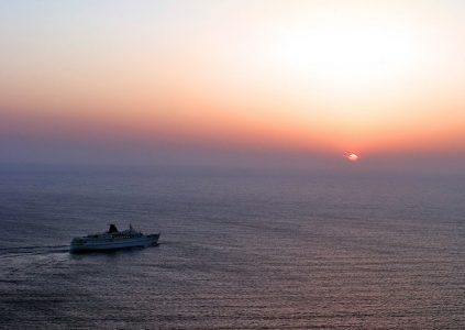 Солнце в закатной дымке и круизное судно.
