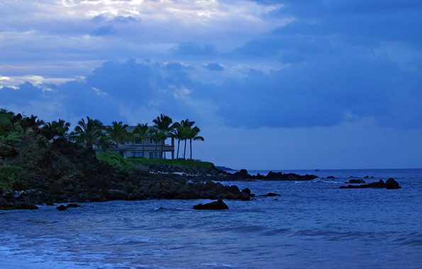 Сумерки над островом и вилла в пальмах на берегу.