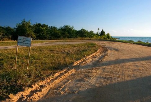 Дорога на полуострове Плаценсия, она же посадочная полоса. Надпись на знаке: "дай дорогу взлетающему или садящемуся самолету". Южный Белиз.