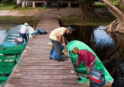 Жители деревни готовят лодку к экскурсии по заповеднику Crooked Tree.