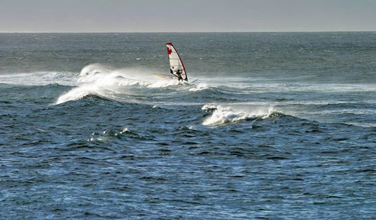 Канадский виндсерфер упражняется на вечерних волнах.