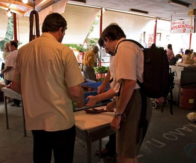 Илья покупает копченую сосиску на рынке в Каламате.