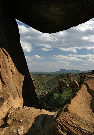 Вид на пустыню через окно, образованное балансирующей скалой.