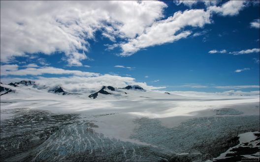 "Аляска подо льдом". Огромное ледовое поле Harding Ice field высоко в горах Kenai Mountains. Добраться туда можно только в июле-сентябре, 15 км туда-обратно по горам. Все остальное время путь покрыт толстым слоем льда и снега. Отсюда же берет начало ледник Exit Glacier, спускающийся с гор синим языком, и испещренный моренами. Многометровые слои льда с расщелинами выглядят довольно устрашающе, но в то же время притягивают насыщенным голубым цветом.