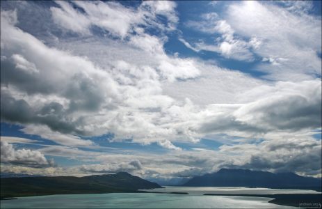 Облака над сине-зеленой водой озера Naknek lake.