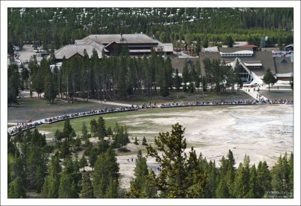 Люди расселись на скамейках в ожидании извержения гейзера Old Faithful.