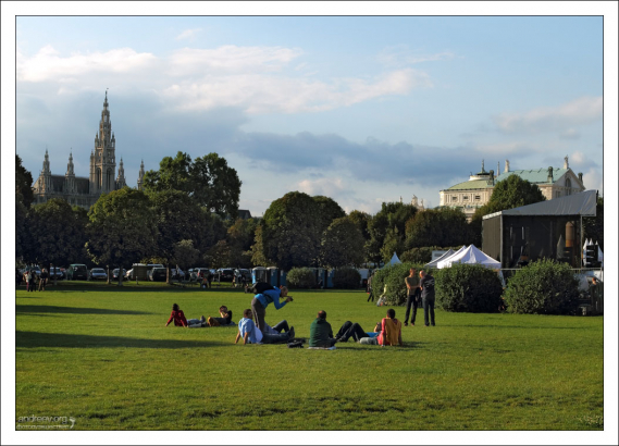 Местные и туристы отдыхают на лужайке перед дворцом Hoffburg.