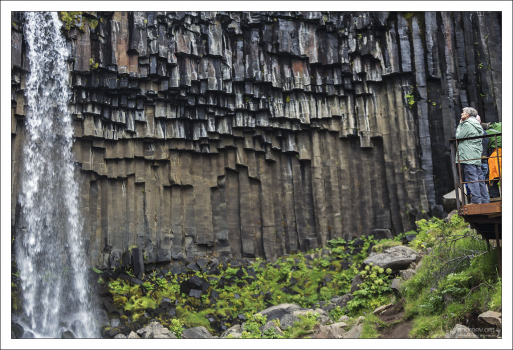 Водопад низвергается на фоне базальтовых столбцов.