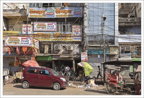 Современная Индия: яркая реклама, клубки спутанных проводов, мусор под ногами, велорикши, и помятые машины.