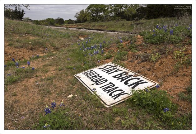 Сорванный знак, призывающий оставаться в стороне от железнодорожной колеи.