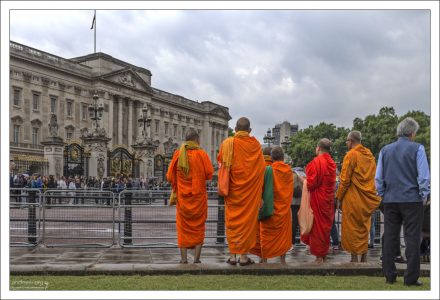Буддийские монахи в традиционных одеждах на фоне Букингемского дворца.