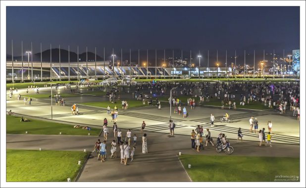 Медаль-плаза и гуляющий вечером народ.