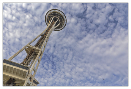 Башня Космическая Игла под необычным углом, и заходящий на посадку самолет.