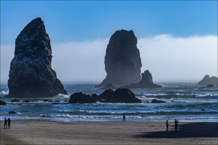 Люди и "Иглы" на пляже Cannon beach, штат Орегон.