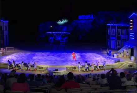 Романтическая песня на сцене, а по холмам в луче прожектора проходят настоящие лошади.