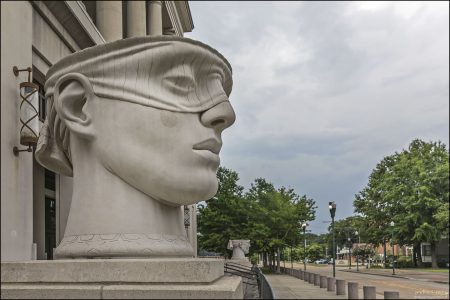 Парная скульптура “Head of Justice” перед зданием федерального суда в Лафайетте.
Напоминает классический образ Фемиды, у которой глаза закрыты, чтобы показывать беспристрастность, но здесь скульптор Diana K. Moore добавила более современный, неоднозначный штрих.