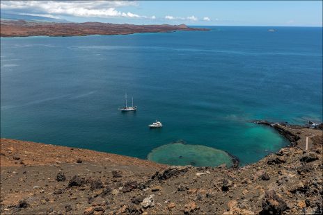 Вода океана контрастирует с чёрной лавой и рыжеватыми склонами острова Бартоломе. При солнечном свете меняет оттенки от синего до зелёного.