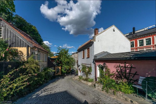 Летний день в историческом квартале. Нарядные разноцветные домики XVIII века на крутом спуске улицы Тельтхусбаккен.