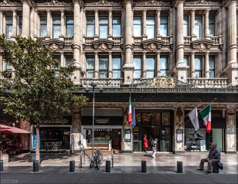 Фасад Gran Hotel Ciudad de México: Монументальный внешний фасад здания, выходящий на площадь Сокало, оформлен в неоклассическом стиле с массивными колоннами и изящными коваными козырьками. На первом этаже у парадного входа отеля сегодня располагаются кофейни и коммерческие заведения.