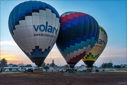 Готовность номер один: Три аэростата компании Volare полностью подняты и зафиксированы на стартовых позициях. Пассажиры уже заняли свои места в корзинах, ожидая финальной команды пилотов на отрыв от земли.
